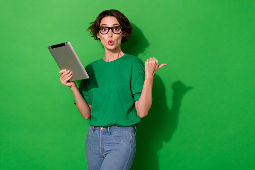 Photo of charming impressed woman dressed summer t-shirt eyewear typing gadget empty space isolated green color background.