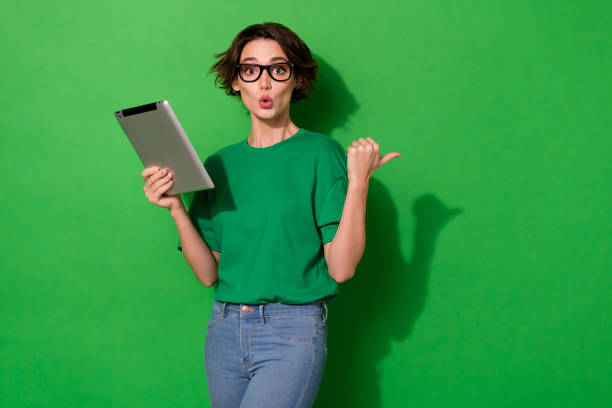 Photo of charming impressed woman dressed summer t-shirt eyewear typing gadget empty space isolated green color background stock photo
