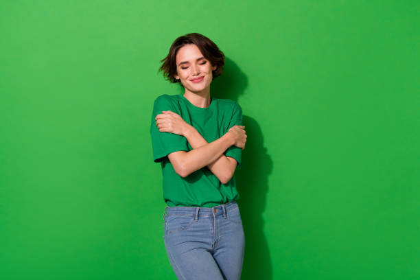 Portrait of lovely gorgeous person closed eyes hug shoulders isolated on green color background stock photo