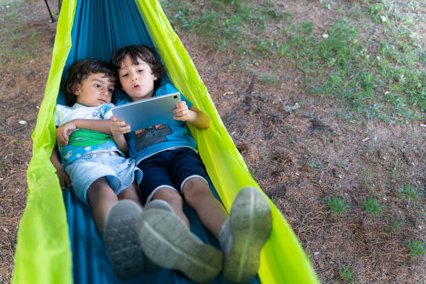 istock two brothers lying in hammock playing game on tablet 1414075449