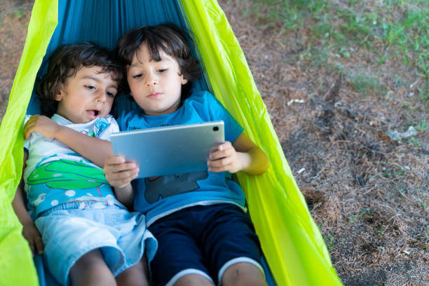 istock two brothers lying in hammock playing game on tablet 1414075487