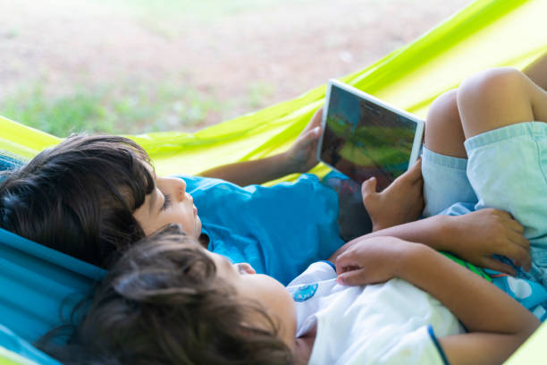 istock two brothers lying in hammock playing game on tablet 1414076083