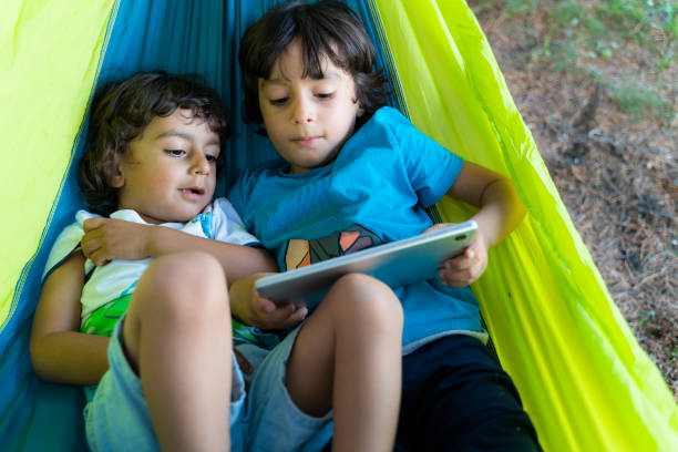 istock two brothers lying in hammock playing game on tablet 1414076138