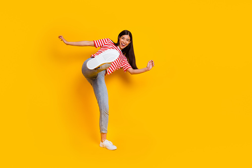 Full body photo of positive overjoyed person have fun raise leg kick isolated on yellow color background.