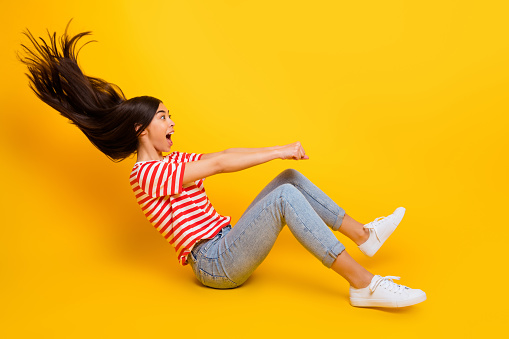 Full size profile photo of excited overjoyed girl hands hold ride empty space isolated on yellow color background.