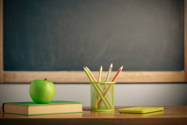 istock Apple on a book on blackboard background. Education concept 1414080493