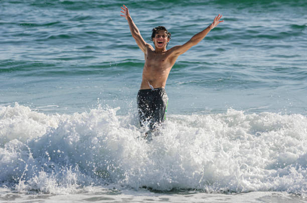 подросток-латиноамериканец �веселится в океанских волнах - skimboard стоковые фото и изображения