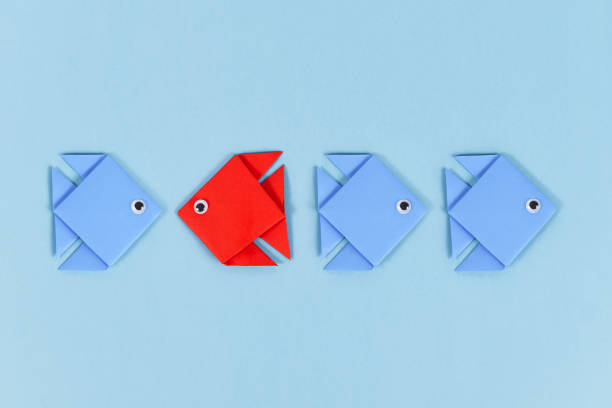 istock Red paper fish swimming swimming against the current 1414083075
