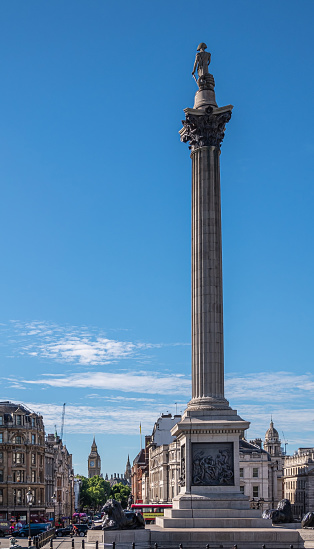 London, UK- July 4, 2022: Trafalgar Square. Nelson's Column in front all the way to Big Ben tower under blue sky. Buildings and traffic in between.