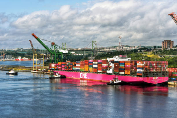 Tugboats assist One Hangzhou Bay container ship head back out to sea Halifax, Canada - July 30, 2022: Tugboats assist the One Hangzhou Bay container ship as it leaves the Fairview Cove Container Terminal in the Bedford Basin in Nova Scotia, Canada. mackay stock pictures, royalty-free photos & images