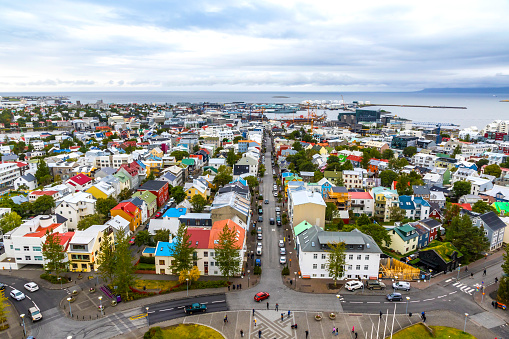 Skyline aerial view of Reykjavik city, Iceland. Skolavordustigur street, downtown, central streets, harbor and ocean scenery beyond the city. View from Hallgrimskirkja Cathedral