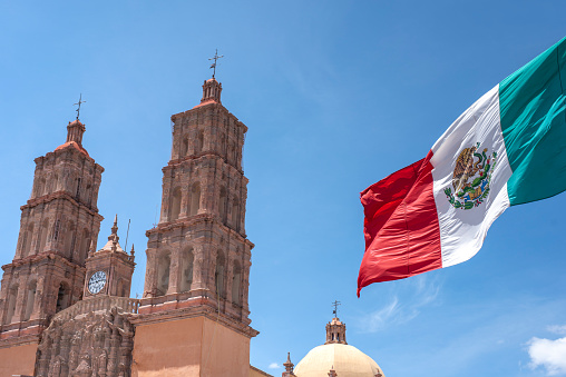 Mexican flag waving with Parroquia Cathedral Dolores Hidalgo Mexico, Cradle of National Independence Where Father Miguel Hidalgo made his Grito starting the 1810 War of Independence in Mexico