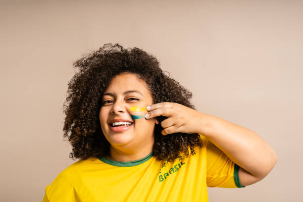 istock Brazilian female supporter applying paint on her face 1414101914