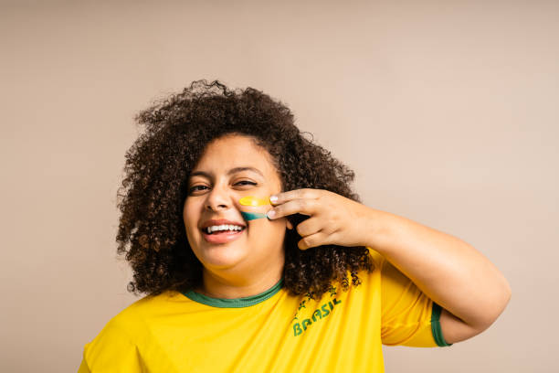 Brazilian female supporter applying paint on her face stock photo
