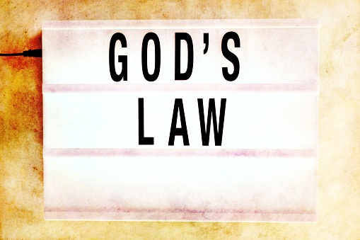 The wording God's Law' in an historically aged Lightbox Theme for Modern Religion. God's Law in simple terms is to love. Love your god, love your family, love other people. And if we can't do that then what have we become?