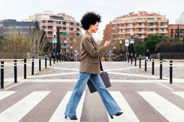 istock business woman walking on a crosswalk using phone 1414107525