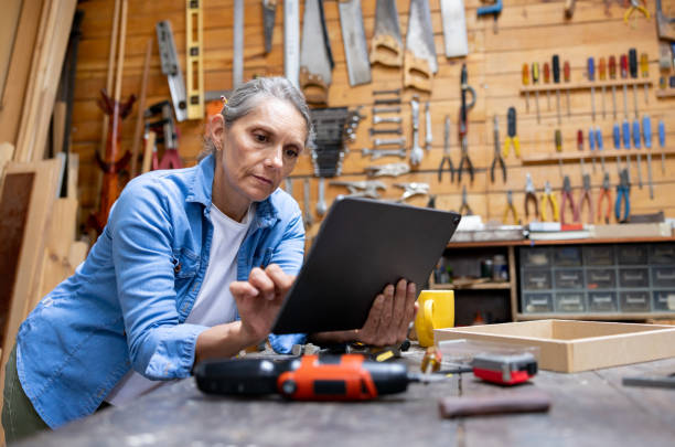 istock Senior woman working in her carpentry workshop and looking at a design on a tablet 1414124790