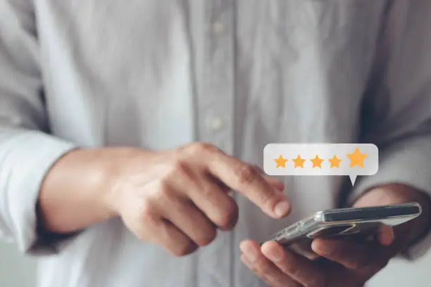 Photo of Customer service and Satisfaction concept, Business people are pressing on smartphone screen with gold five star rating feedback icon to give score point to review the service