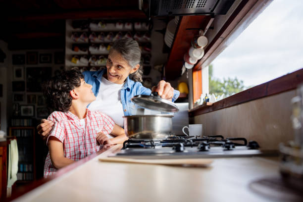 Happy grandmother cooking dinner at home with her grandson - domestic life concepts