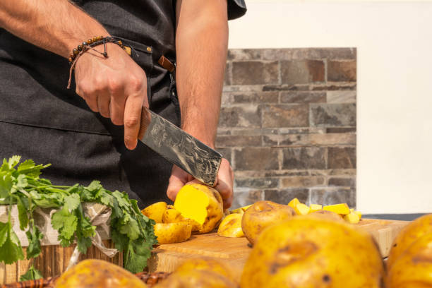 istock Man chopping potatoes in a table in a garden 1414127178