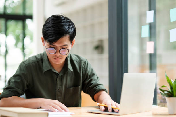 Young asian business man or student working online on computer laptop. stock photo