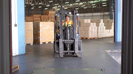 Warehouse staff driving a forklift in the parcel - logistics warehouse.