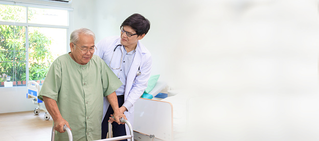 Elder Asian man practicing a physical therapy with professional therapist in hospital. Physiotherapist helping an elder man doing a physical therapy.