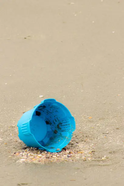 empty lone bucket left unattended on sand at the beach, pollution, litter, lost toy
