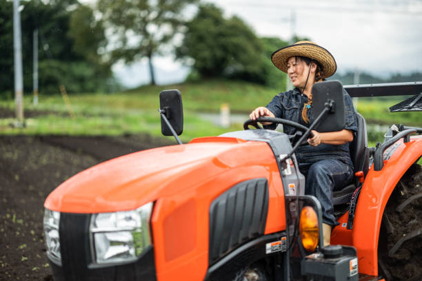 Japanese female farm worker driving a tractor stock photo