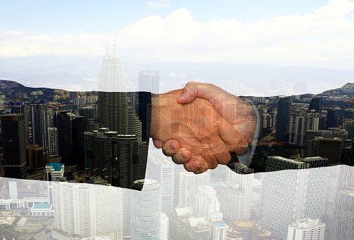 Business hand shake concept with abstract office buildings in background