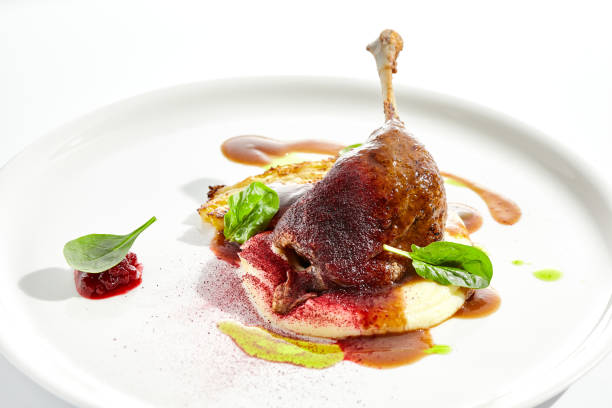 istock Delicatessen dish - duck leg confit with mashed potatoes and cabbage steak. Duck confit with vegetables and wine gravy on white plate. Gourmet meal in restaurant menu. Fusion main course. 1414134409