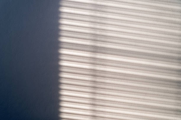 istock Sunlight passes through the blinds and falls on the wall casting streaks of light and shadow. 1414141422