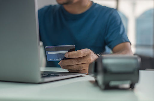 Hands holding credit card and using laptop. Online shopping, Online payment,Man's hands holding a credit card and using smart phone for online shopping.
