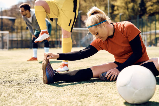 istock Young soccer player stretching her leg while warming up on playing field. 1414147277