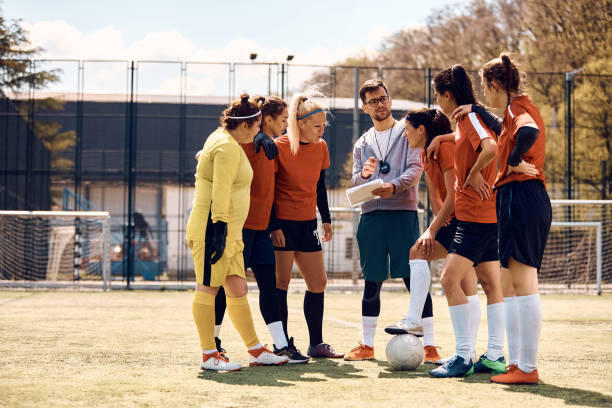istock Soccer coach planning game strategy with female team on playing field. 1414149515