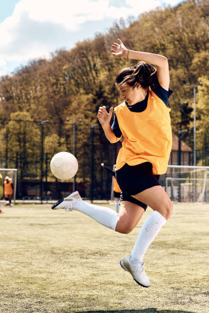 istock Skillful female player practicing with soccer ball on playing field. 1414150224