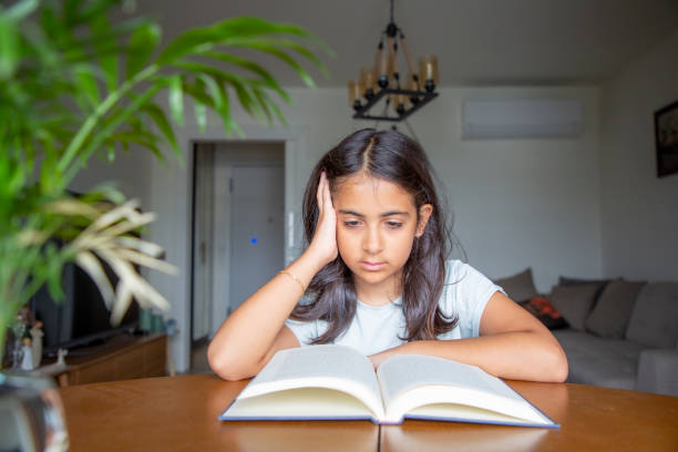 istock Little girl reading a book 1414150897
