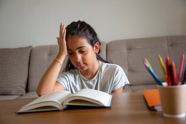 istock Girl sitting at table at home doing homework and using laptop 1414151573