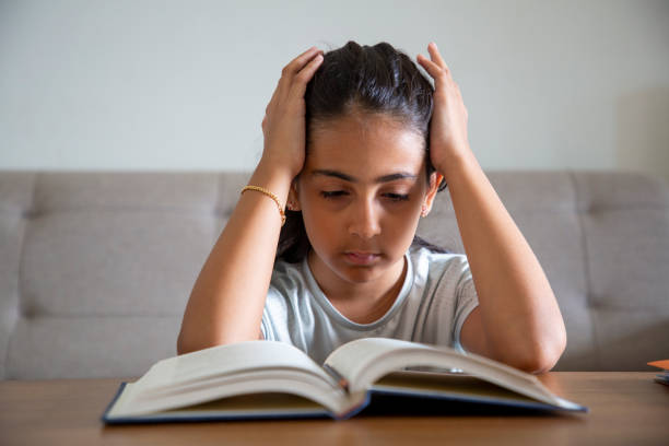 istock Girl sitting at table at home doing homework and using laptop 1414151645