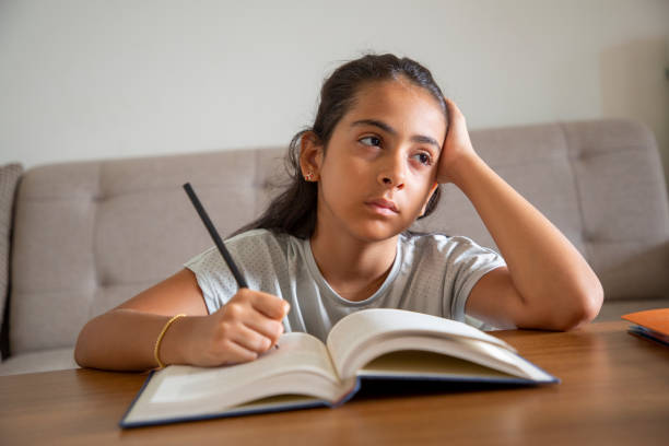 istock Girl sitting at table at home doing homework and using laptop 1414151659