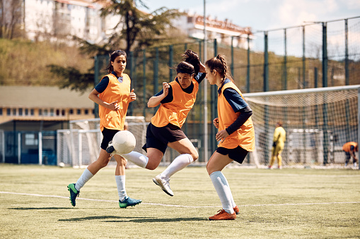 Soccer player practicing with her teammates during sports training on playing filed.