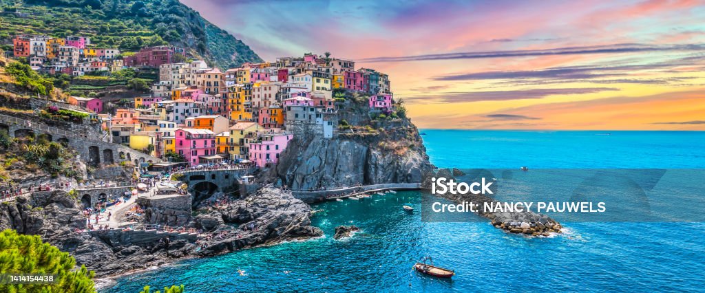 Panoramic view of picturesque village Manarola, Cinque Terre, Italy. Beautiful landscape with colorful buildings on the hill along the coastline. Popular tourist destination. Manarola, one of the five villages of National Park Cinque Terre, La Spezia, Liguria, Italy, Europe. Wide image. Italy Stock Photo