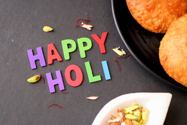 Assorted Indian Mahashivratri or Holi festival food like samosa, kachori, Kaju Katli, Puran Poli, dry fruits & Almond milk Thandai drink with Happy Holi wishes over black background with copy space. una variedad de mahashivratri indio o comida del festival holi como pav bhaji, dahi vada, gujiya, puri bhaji, gulab jamun, samosa, kachori, kaju katli, puran poli, frutas secas y leche de almendras bebida thandai con deseos happy holi sobre fondo negro con