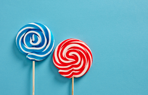 Colorful swirl round candy lollipops on blue background.