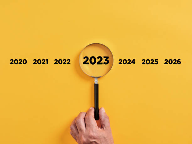 la mano masculina sostiene una lupa centrada en el año 2023. enfoque en nuevos objetivos de negocio, plan y estrategia del año 2023 - planning organization leadership budget fotografías e imágenes de stock