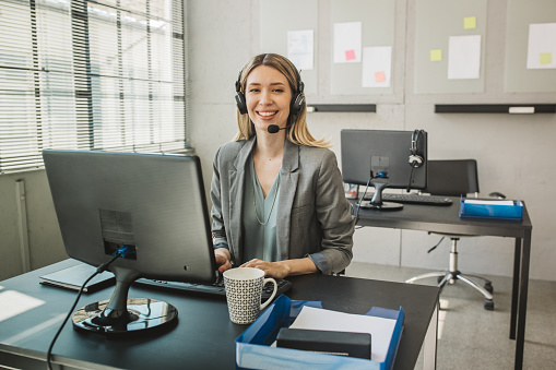 Friendly woman in call center service talking with costumers by headset.