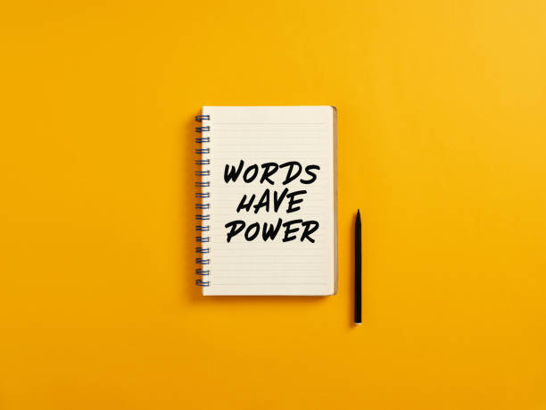 le bloc-notes et le stylo noir sur fond jaune avec les mots de message ont de la puissance. - single word photos et images de collection