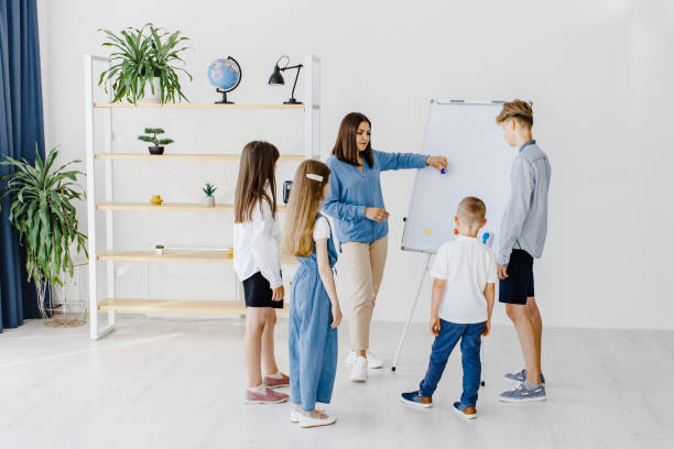 istock Explaining lesson and using board. Group of children students of different ages in class at school with teacher. Learning concept 1414164395