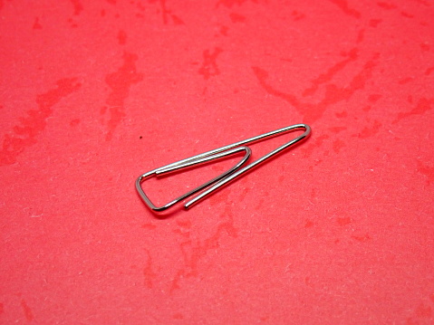 office stationery trigonal clip or paper clip on a red background