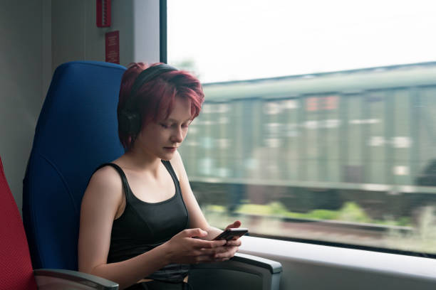 スマホに浸かって電車に乗る若い女性 - medium group of people audio ス��トックフォトと画像